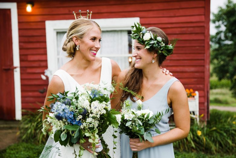 bride with tiara and bridesmaid with floral crown in front of red wall