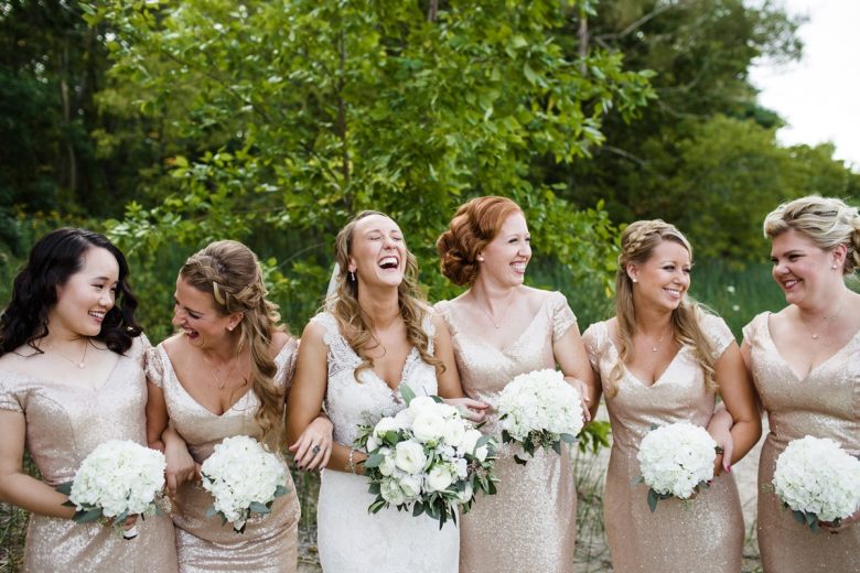 bride and bridesmaids holding bouquets laughing