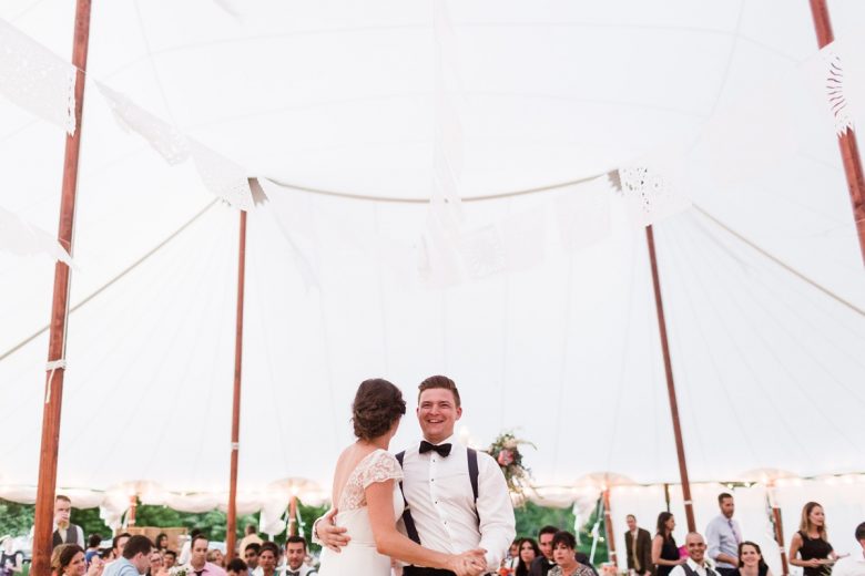 bride and groom in black bowtie beneath white tent