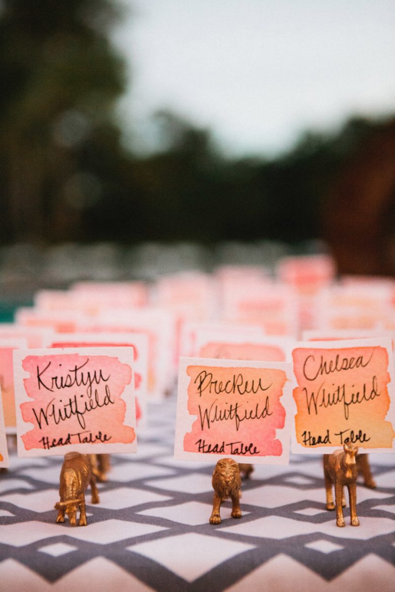 Ombre watercolor place cards in gold plastic animal holders.