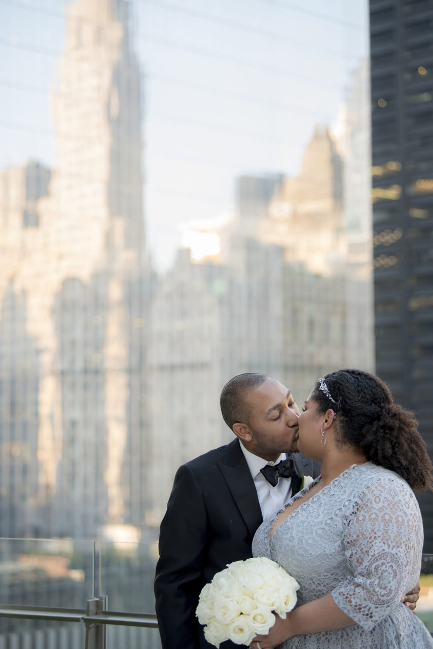 A wedding couple kiss with the skyline behind them.