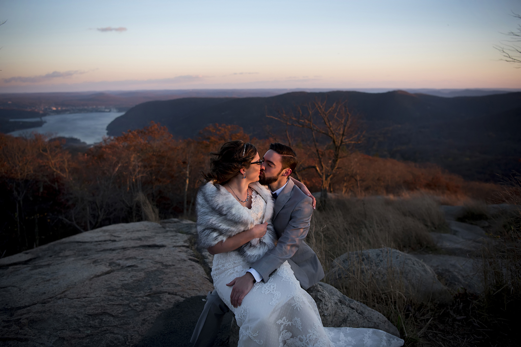 A couple kiss on a mountain top at sunset