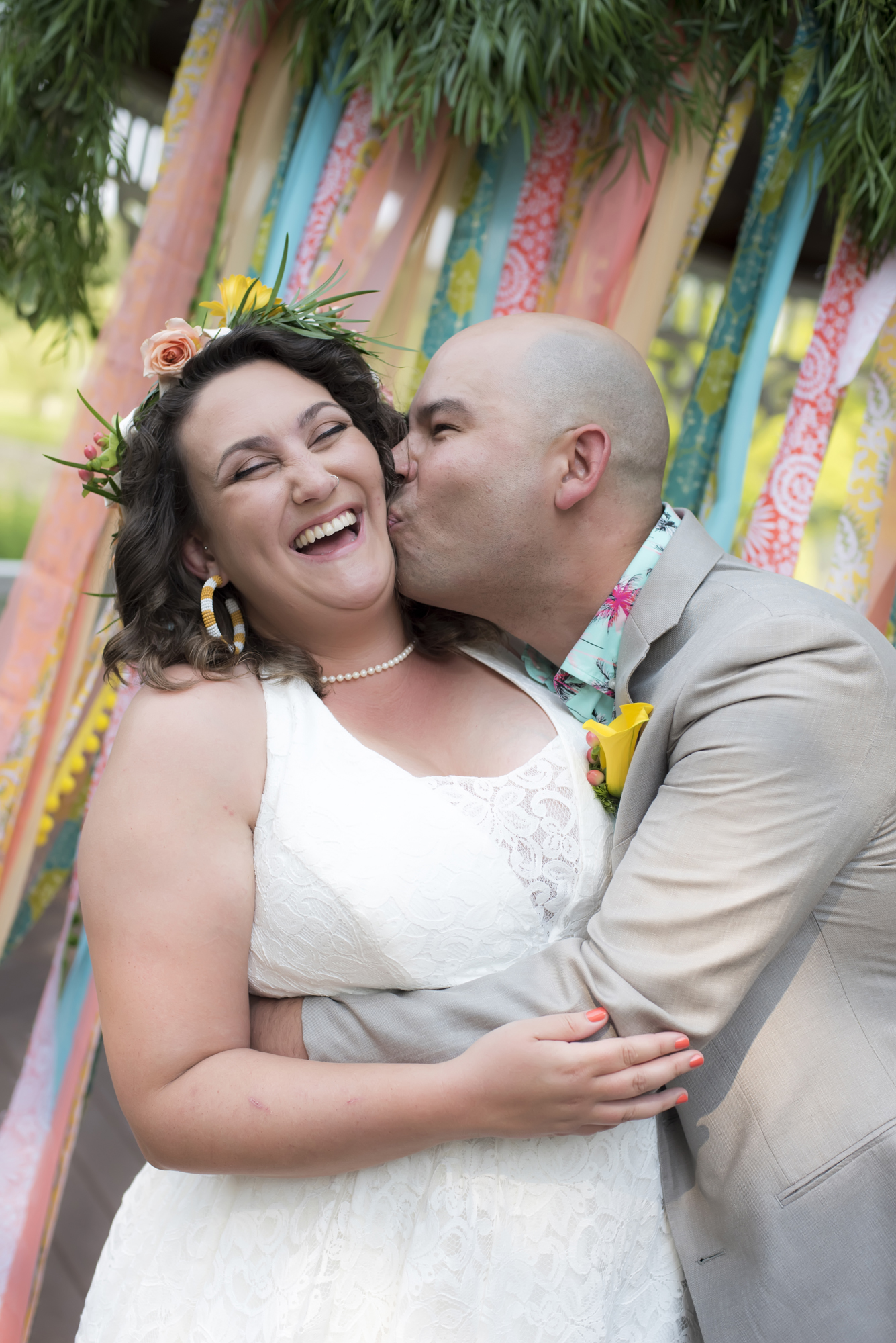 A man kisses a woman's cheek on their wedding day.