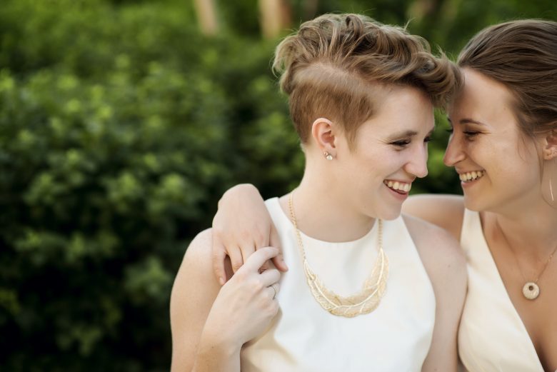 two brides with heads together, smiling