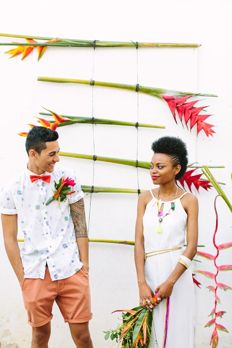 bride and groom stand in front of tropical flower ladder 