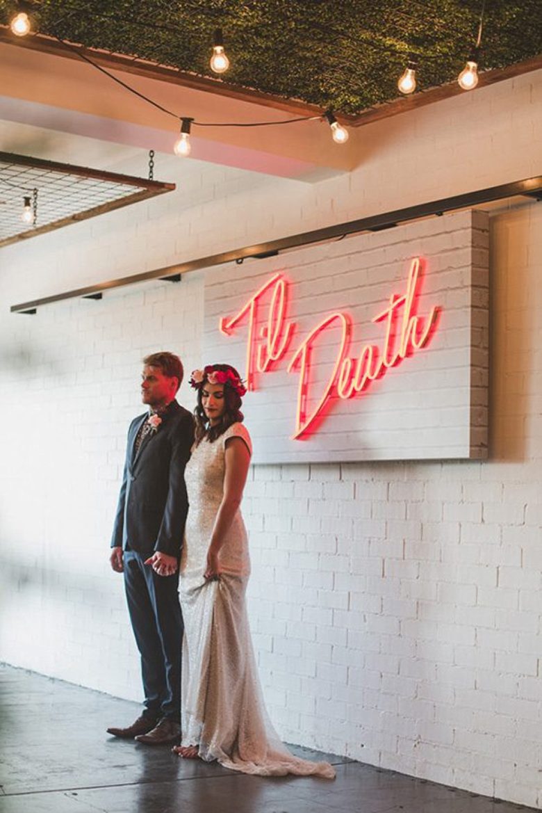 bride and groom stand in front of neon-style sign that reads, "'Til Death"