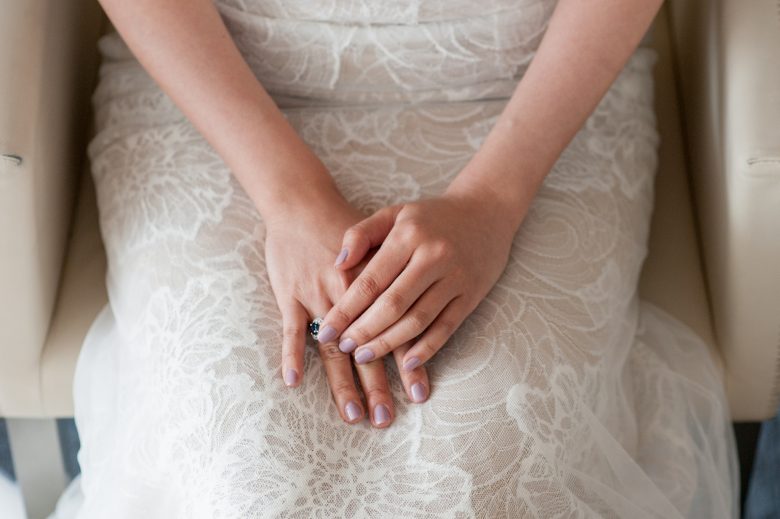 A bride sits with her hands folded in her lap