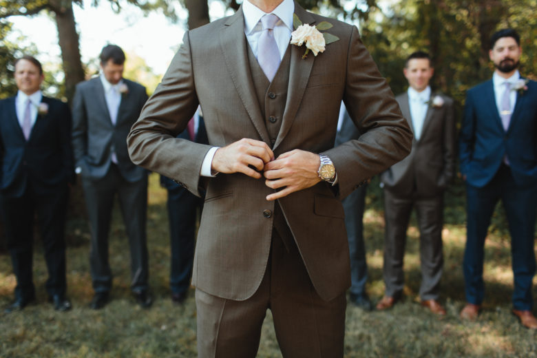 A groom buttons his suit