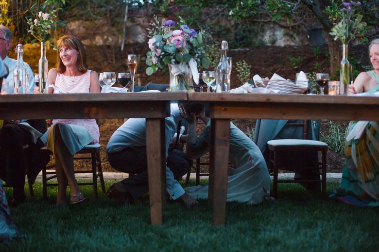 bride and groom kissing underneath banquet table in garden in a Gina Clyne photo