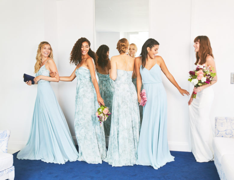 Group of four bridesmaids wearing blue floral gowns and a bride.