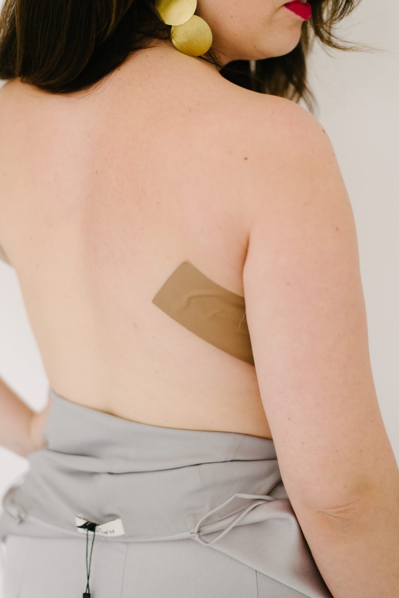 woman's bare back with a small piece of tape showing