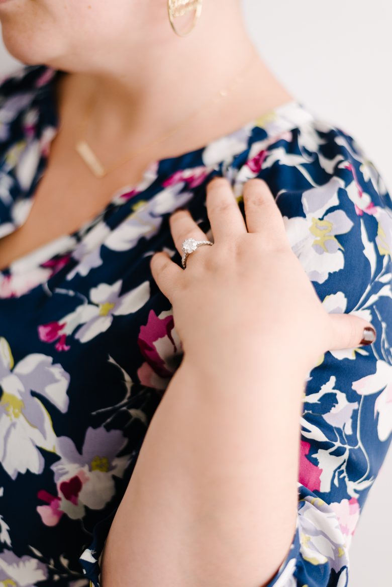 woman touching her shoulder, showing off her engagement ring