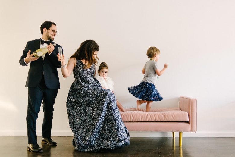 children running on a couch while parents prepare wine