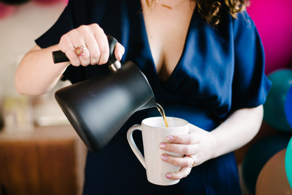 woman pouring tea from a black matte tea kettle into marin coffee mug from crate and barrel