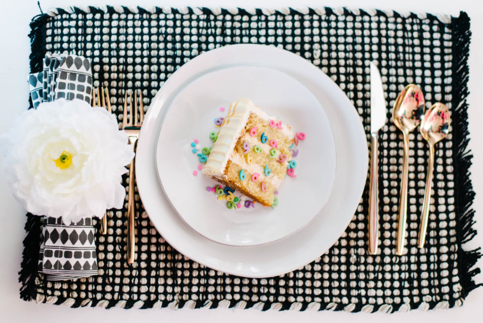 slice of wedding cake with number nine sprinkles on it on marin dinnerware with peony napkin ring and patterned black and white linens from crate and barrel
