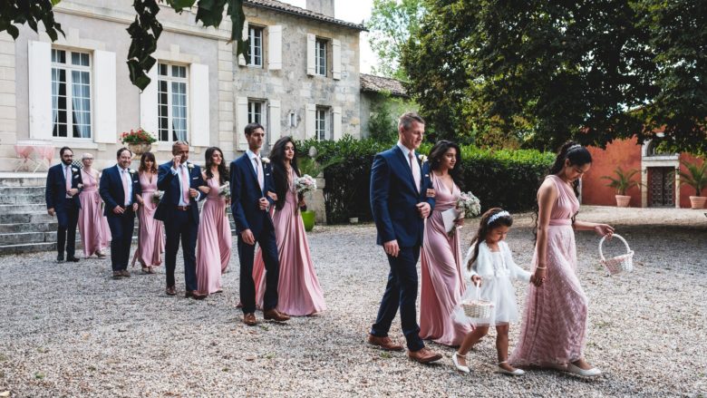 processional of bridesmaids in pink dresses and groomsmen in blue suits through gravel yard