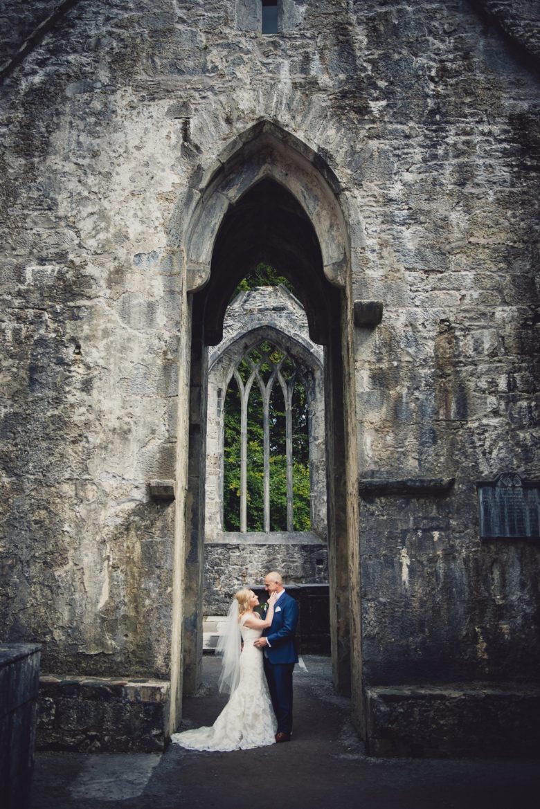 bride and groom embracing under a tall castle archway