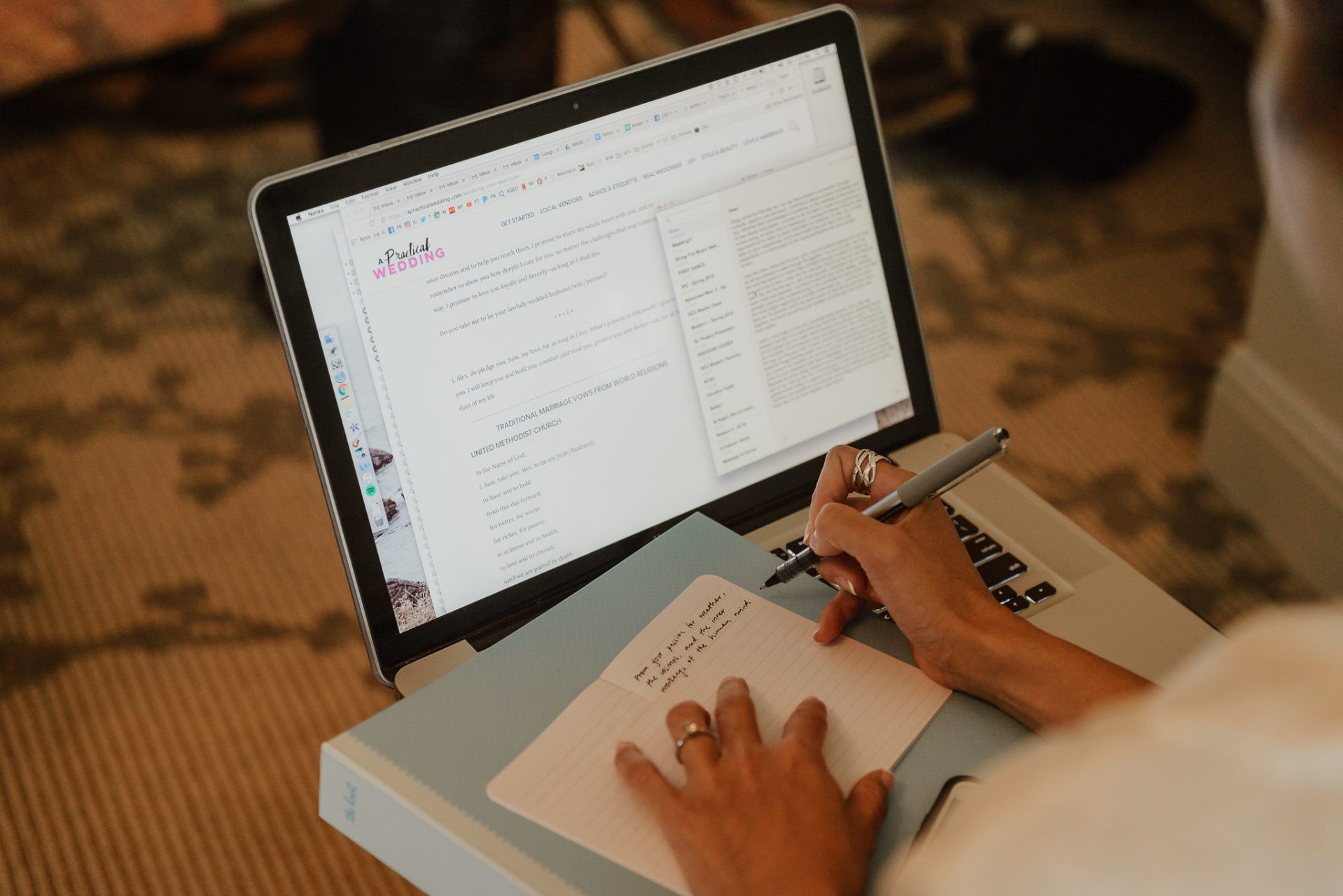 a woman writes her wedding vows in a small notebook with A Practical Wedding's wedding vow checklist pulled up on her screen