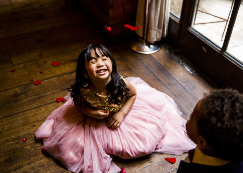little girl in pink tutu sitting on the floor laughing