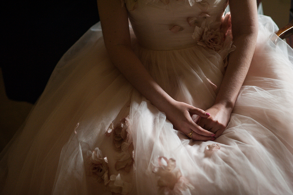 close-up shot of bride's hands resting on her lap in tulle dress with embroidered flowers in a photo by You Are Raven
