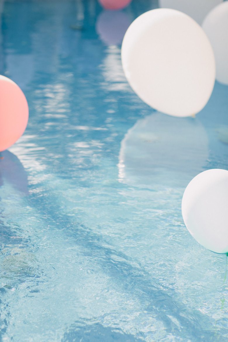 pink and white balloons floating in a swimming pool