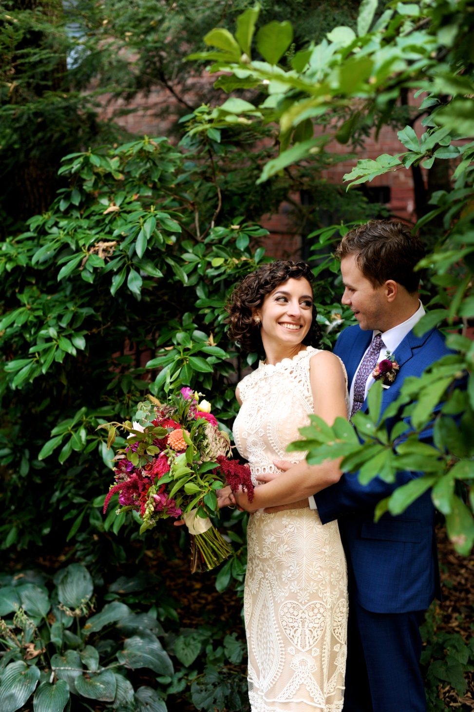 portrait of bride and groom surrounded by greenery