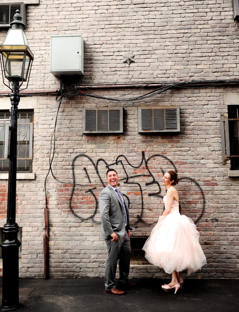 a bride and groom pose in front of graffiti