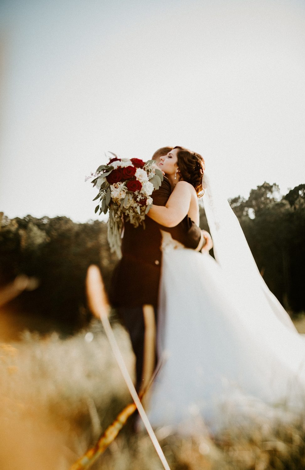 a wedding couple embracing in a field