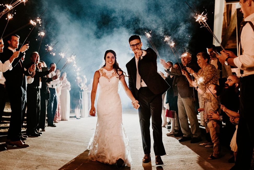 couple walking through sendoff line holding sparklers
