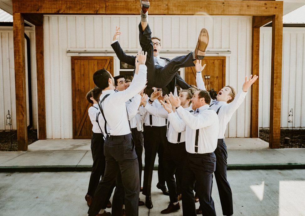 groomsmen throwing the groom in the air