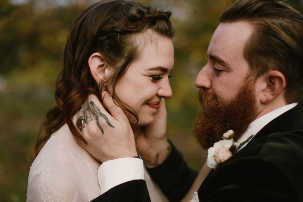 groom with tattooed hands holding bride's face