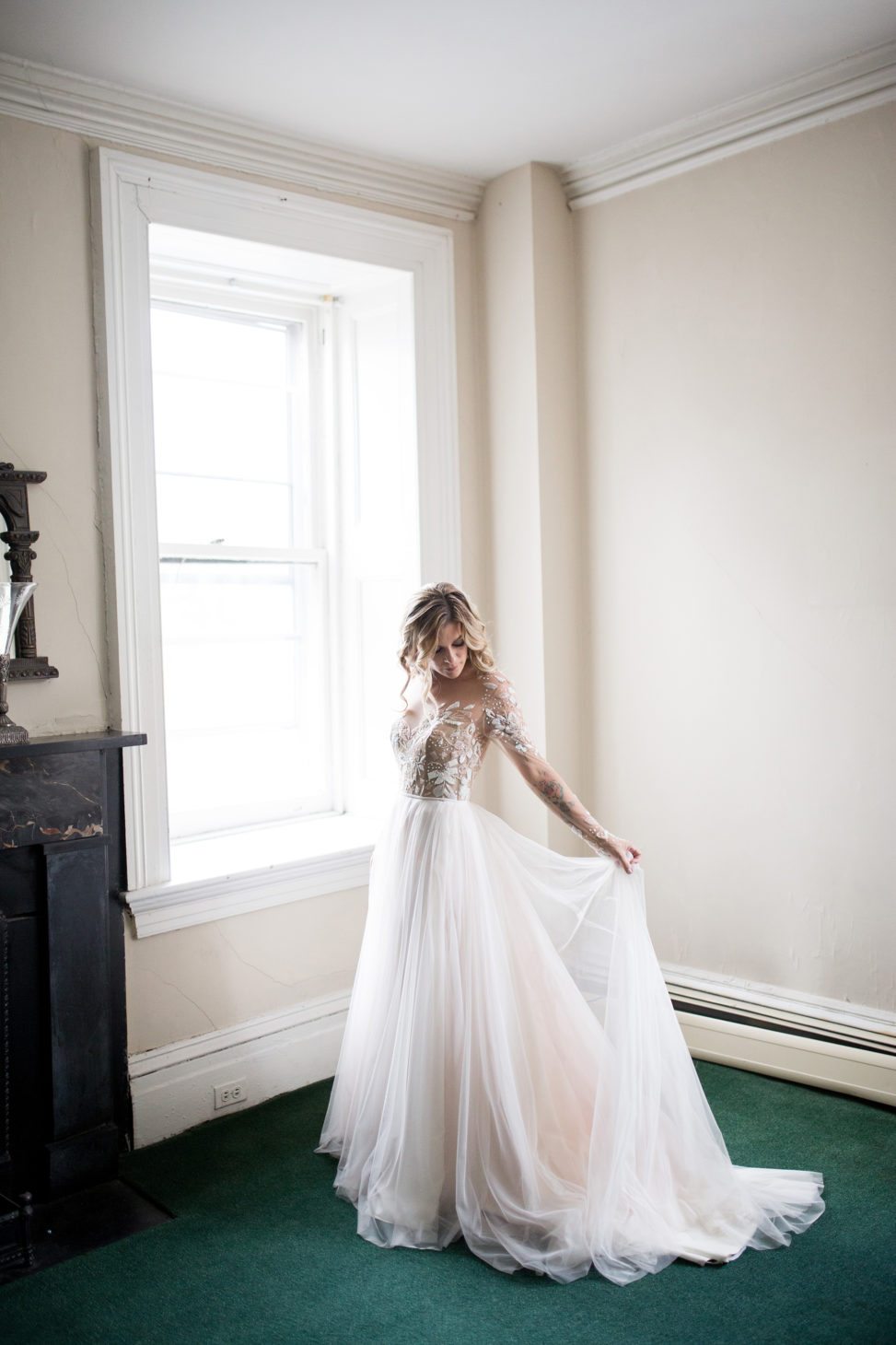 bride in white room with green carpet adjusting train