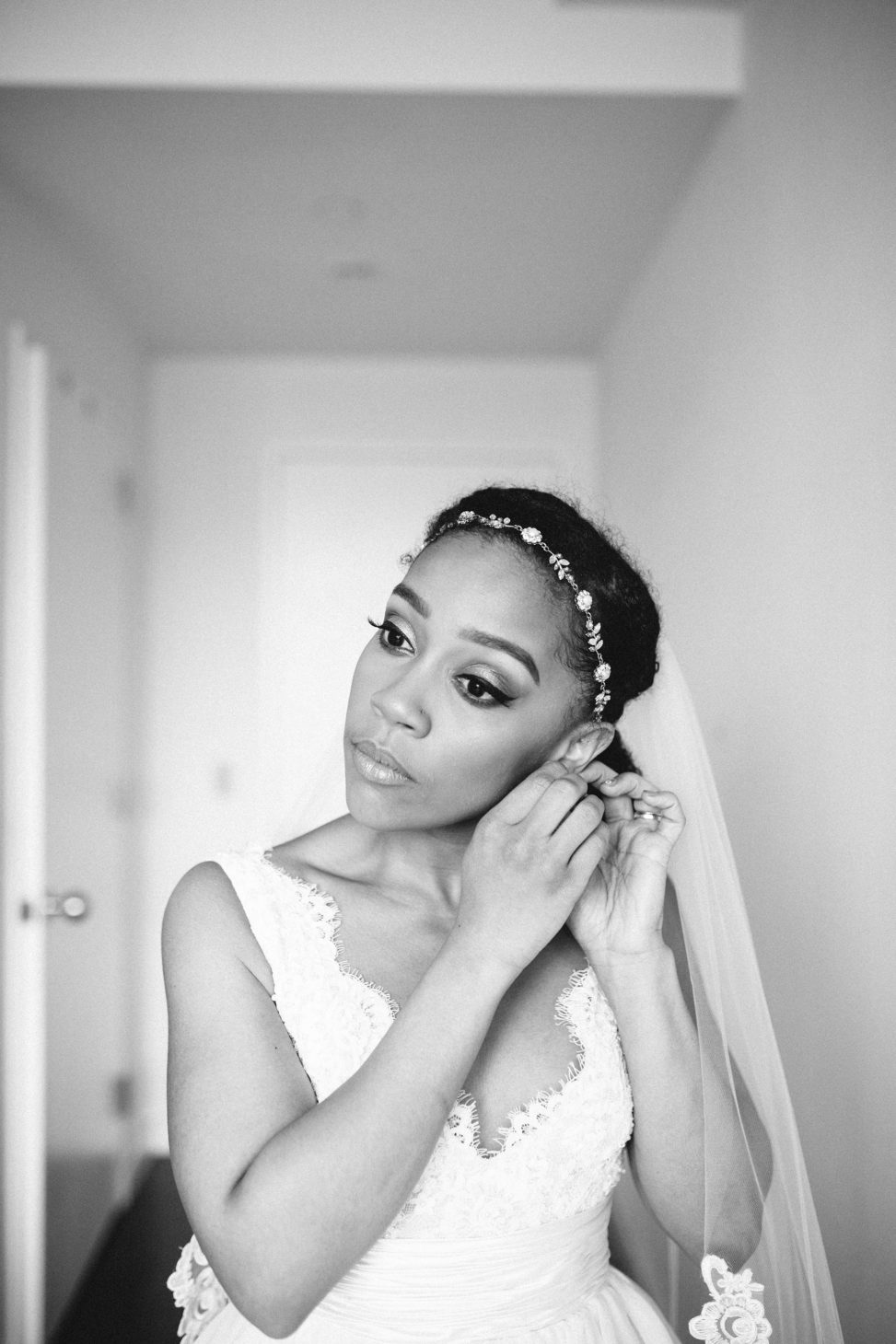 black and white photo of black bride adjusting her earring