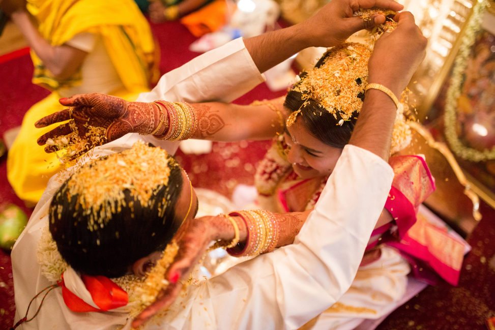 Indian groom and bride with mehndi tossing rice on each others heads