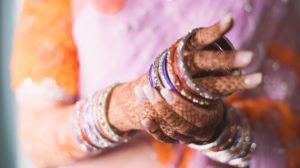 female hands with mehndi putting on sparkly bangle bracelets