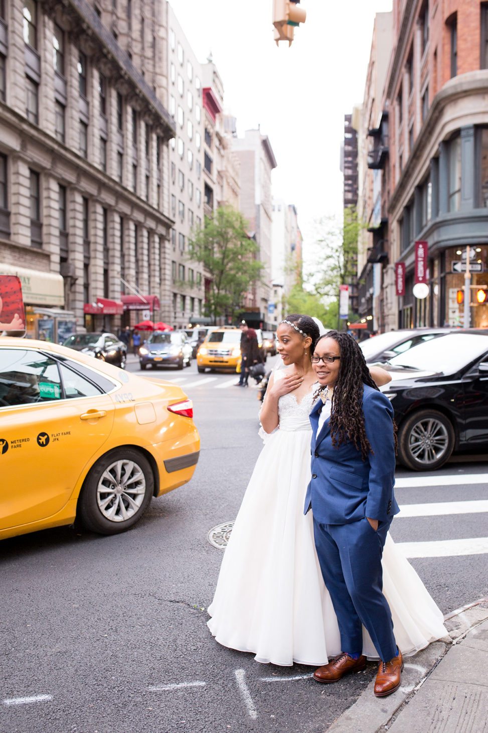 bride in tulle gown and bride in blue suit standing in NYC street