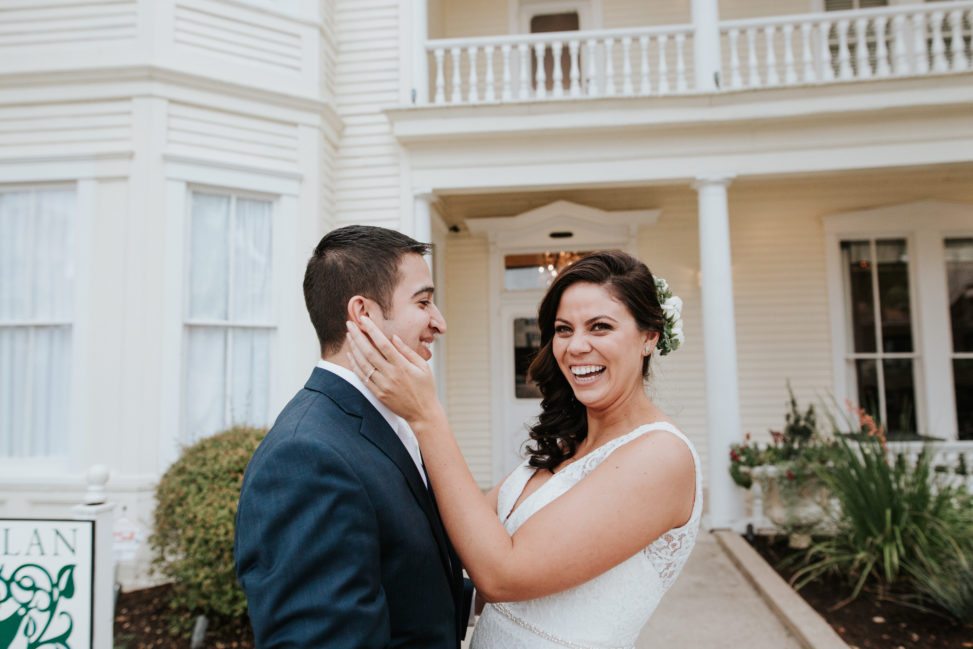 woman wearing a wedding dress holding her partner's face and laughing