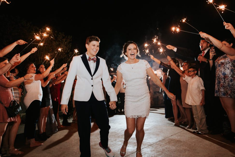 lgbtq couple exiting wedding surrounded by guests with sparklers