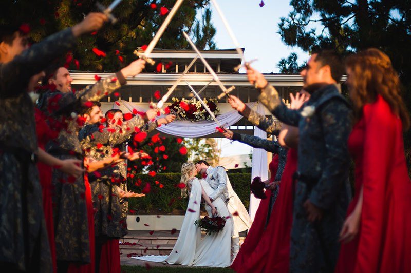 bride and groom kiss in front of swords
