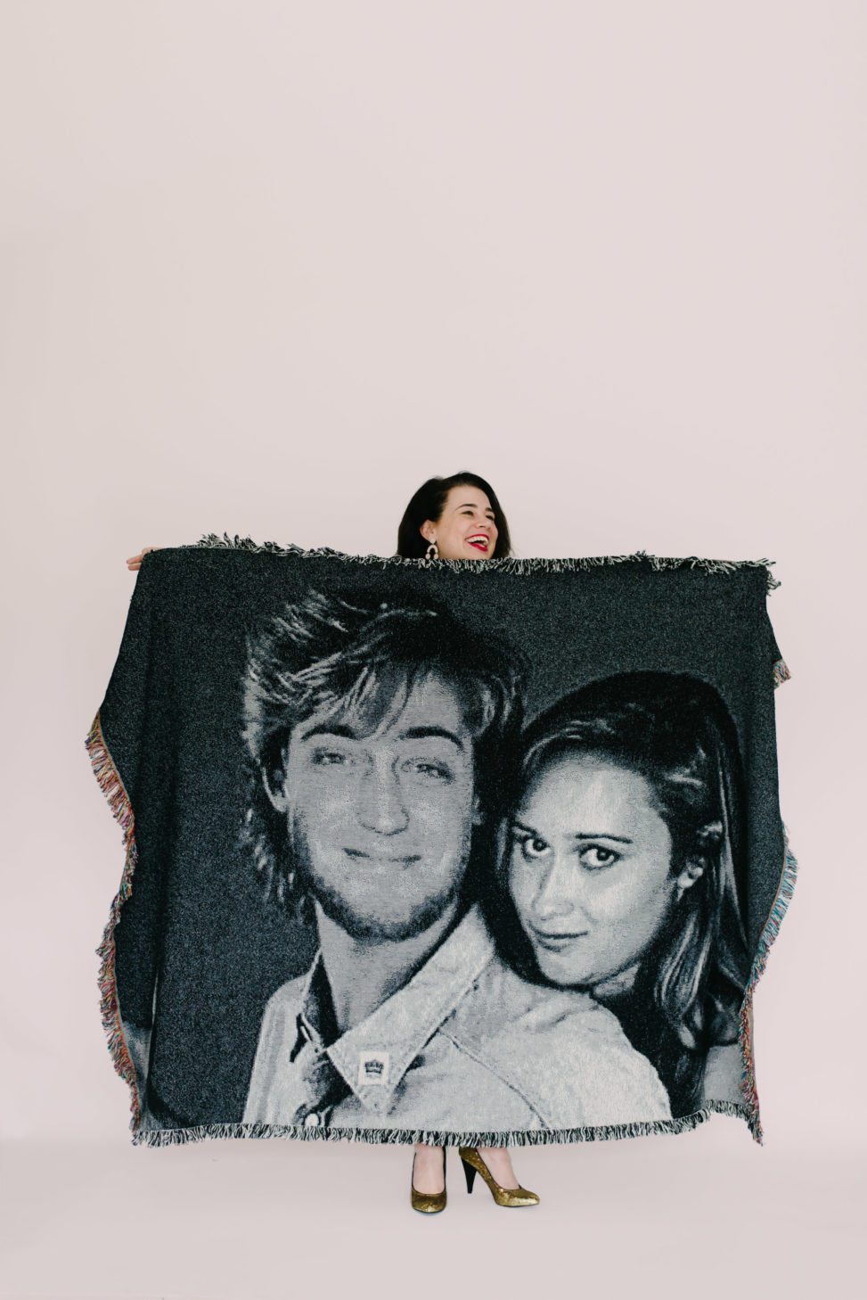 woman laughing and holding a woven blanket from shutterfly featuring a photoshopped image of a couple