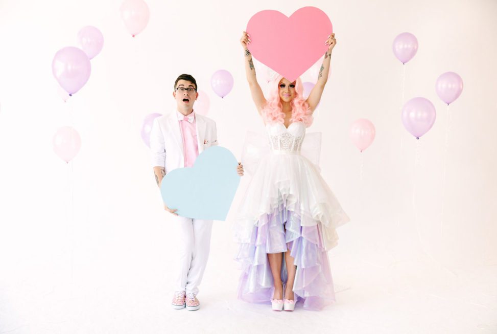 couple wearing colorful formal wear and holding heart props
