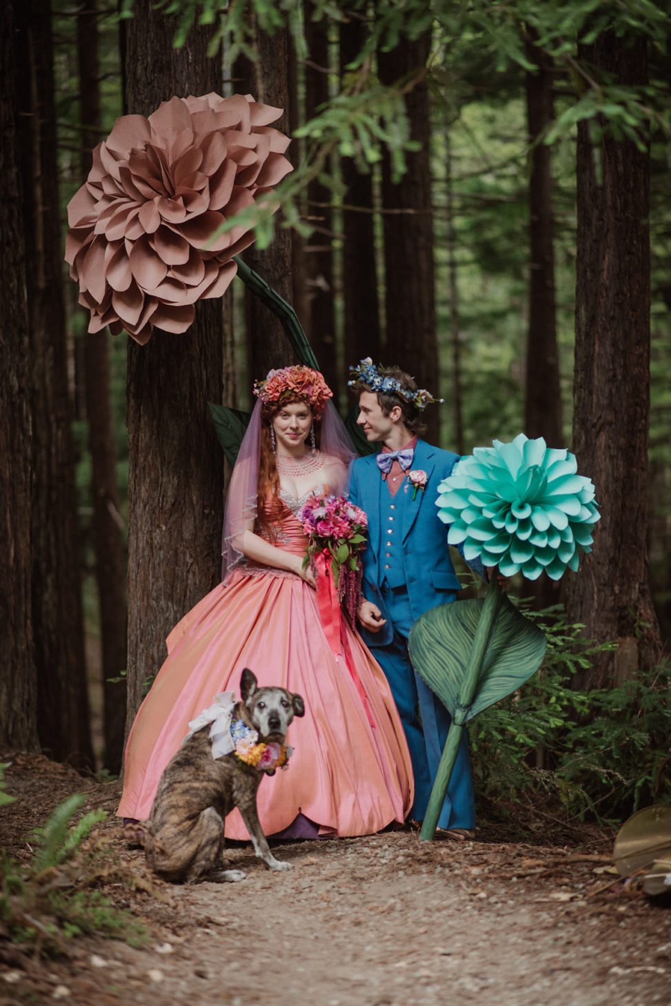 couple wearing colorful Victorian style outfits with with artificial flowers and a dog