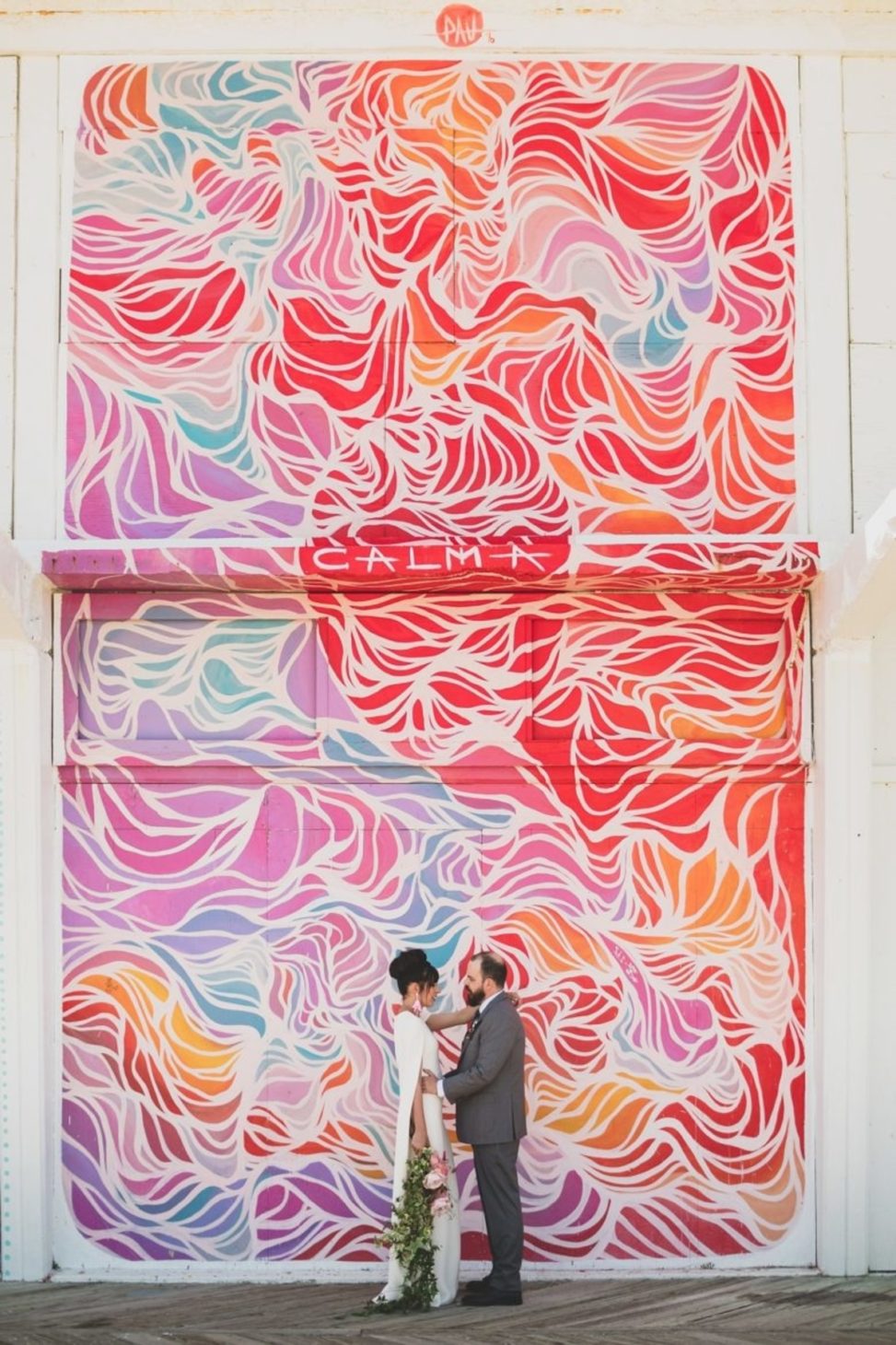 couple embracing in front a mural