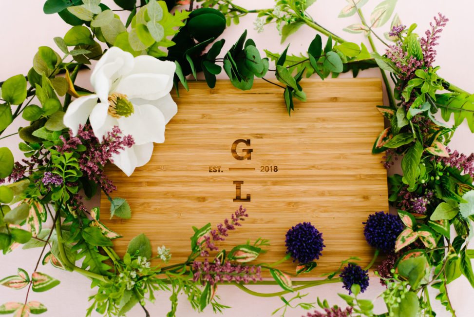 personalized cutting board with initials, surrounded by flowers and greenery