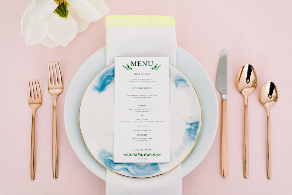 place setting featuring marble plate, gold silverware and printed menu from Shutterfly on a pink background