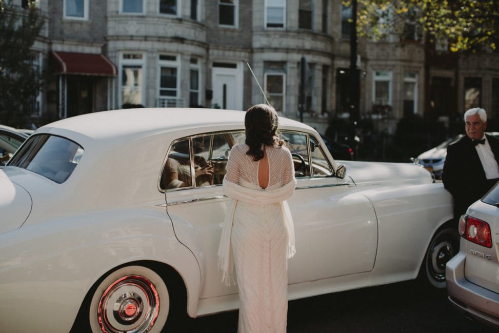 bride wearing vintage dress in front of a classic car