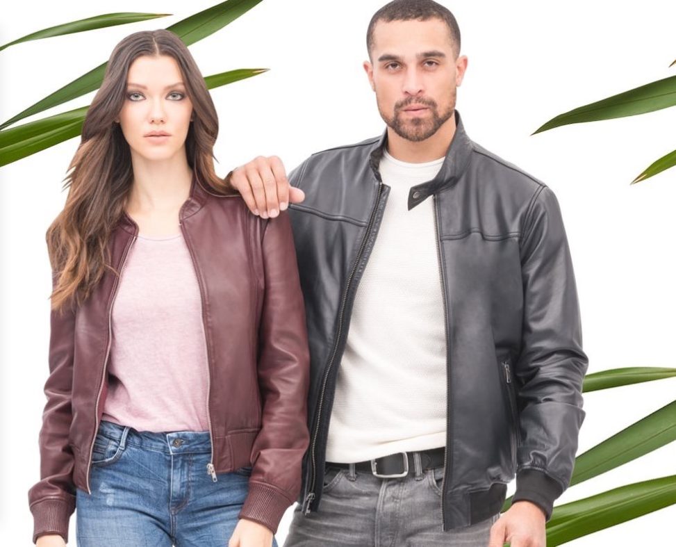 Man in black leather jacket and woman in red leather jacket in front of leaves