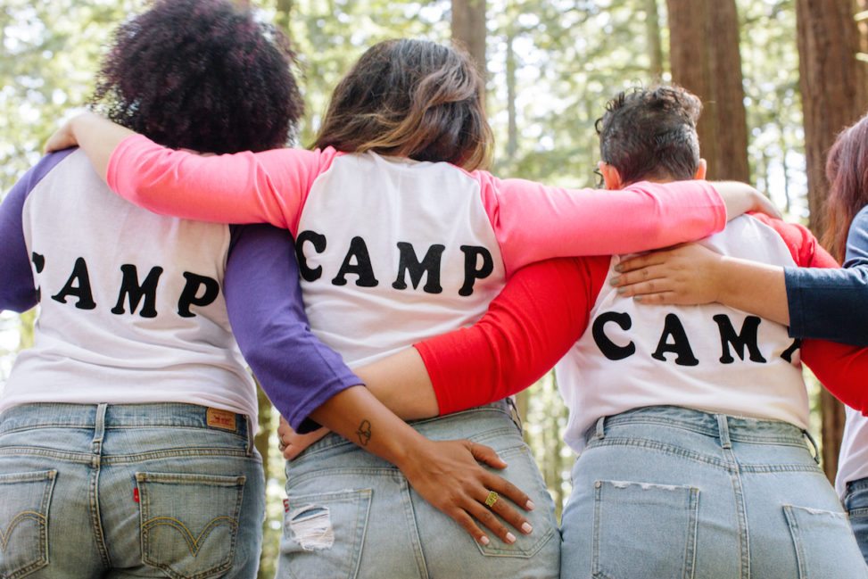 women wearing Camp tees in the woods, with their arms around eachother