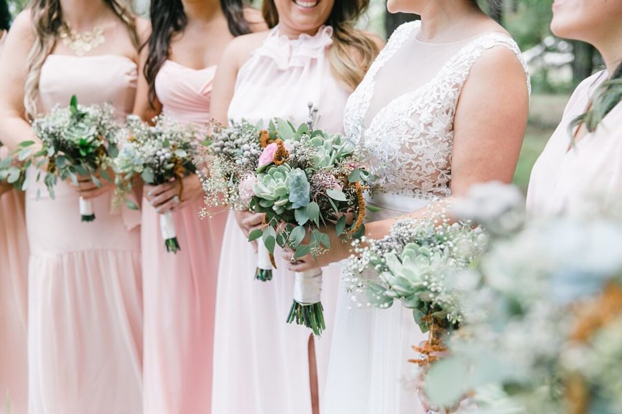 Torsos of bide holding bouquet next to several bridesmaids in pink, holding bouquets