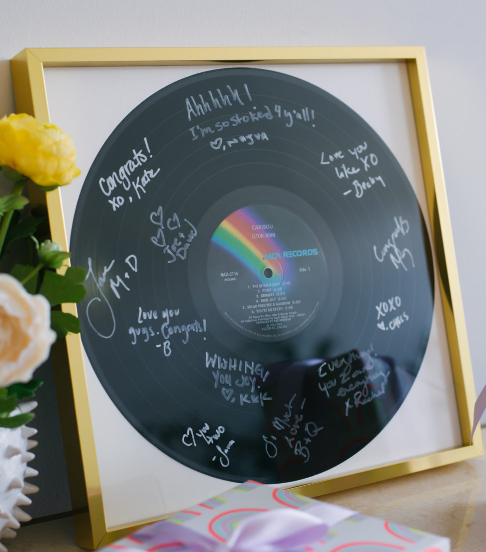 signed record in a gold frame sitting on a table surrounded by flowers and gifts